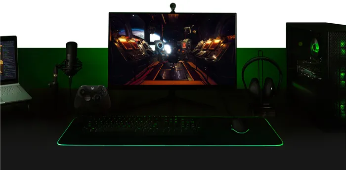 Рабочий стол компьютера, экран внешнего мира, клавиатура, геймпад Xbox One, микрофон и ноутбук, сконфигурированные как единая система.